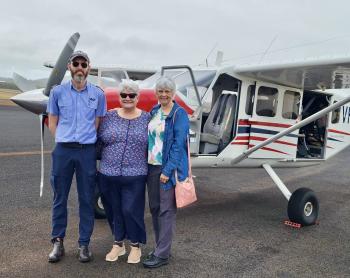 Pilot and passengers standing on tarmac in front of GA8 aircraft