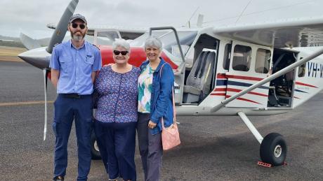 Pilot and passengers standing on tarmac in front of GA8 aircraft