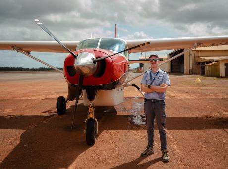 Pilot standing on tarmac in front of plane