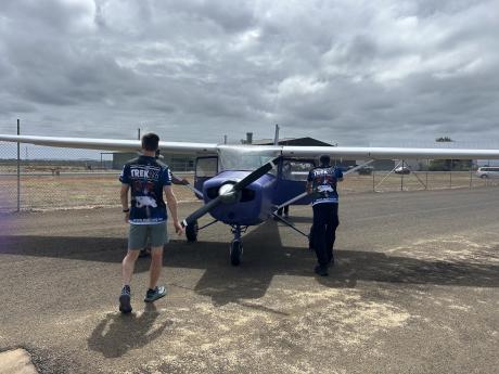 people wheeling small plane along tarmac
